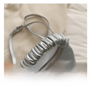 Detail shot of the metallic silver handbag featuring a soft pleated cloud handle design