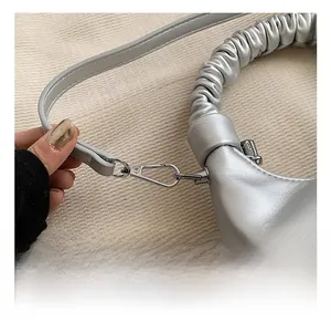 Detail showing the metallic silver clasp and pleated leather handle of the shoulder bag