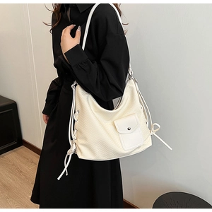 Détail du sac cabas tissé blanc cassé avec liens en cuir et poche à boucle métallique chic