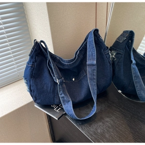 Detail of blue denim hobo bag featuring frayed edges and adjustable silver buckles