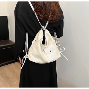 Vue de dos d'une femme portant un sac à dos tissé beige avec poche à rabat et fines bretelles