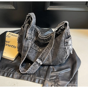Detailed view of frayed raw edges and adjustable strap on washed black denim hobo bag