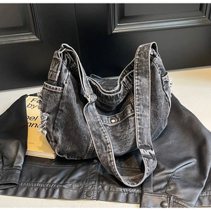 Detail of distressed black denim hobo bag featuring frayed edges and vintage textures