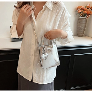 Détail du petit sac carré en cuir ciré argenté avec pendentif cœur sur modèle
