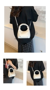 Detail of a creamy white dumpling bag with a pleated scrunchie handle and shoulder strap