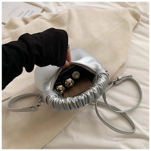 Detail view of the silver dumpling bag interior holding lipstick and compact powder