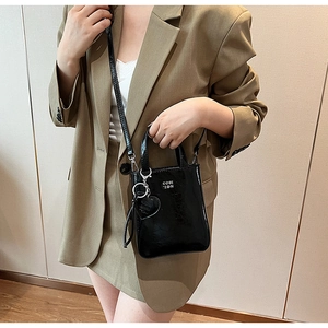 Détail d'un sac à main noir en cuir ciré avec breloque cœur et texte du logo blanc