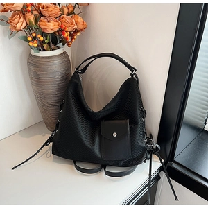 Détail de la texture tressée et poche à rabat sur un sac cabas en similicuir noir
