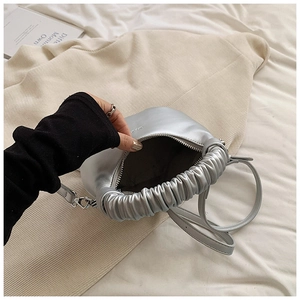 Detailed view of silver pleated handle handbag with metallic finish and zipper closure