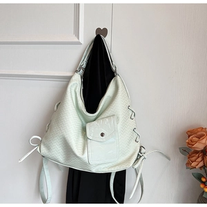 Détail du sac hobo vert menthe avec texture tissée et nœud latéral à œillets argentés