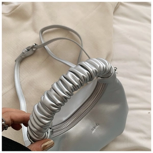 Close-up of a metallic silver dumpling bag with unique pleated handle and zip closure