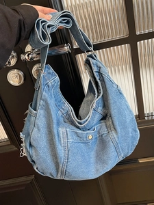 Large blue denim hobo crossbody bag with front pocket and distressed frayed edges