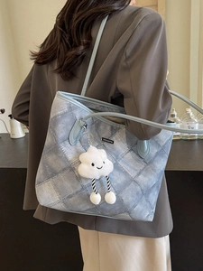Blue denim quilted tote bag with long straps and cute cloud charm shown on shoulder