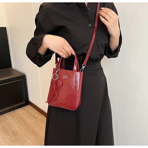 Vue détaillée du sac en cuir verni rouge avec breloque cœur et bandoulière