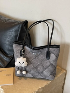 Grey quilted tote bag with black straps and cloud charm on stone base
