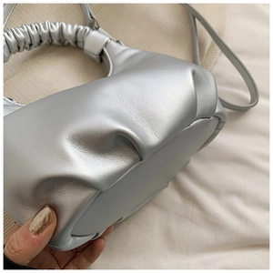 Close-up of metallic silver pleated cloud bag with gathered handle and shiny leather texture