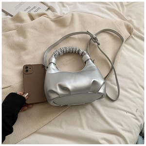 Detail of silver pleated dumpling bag next to a mobile phone for size comparison