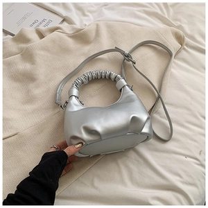 Close-up of metallic silver dumpling bag with gathered handle and adjustable strap