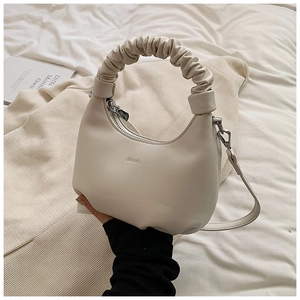 Detail of cream crescent bag featuring a scrunchie handle and embossed brand logo