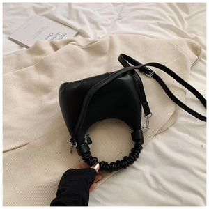 Detail of black matte leather dumpling bag with gathered handle and adjustable strap