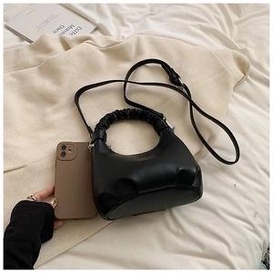 Detail of matte black PU leather dumpling bag with ruched handle and adjustable strap