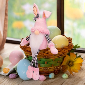 Pink Easter gnome plush with long bunny ears sitting among decorative eggs and flowers