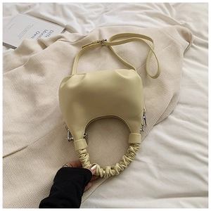 Detail of light yellow dumpling bag featuring pleated handle and silver metal hardware