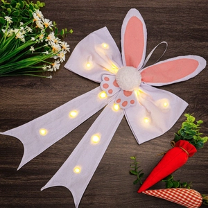 Close-up of Easter bunny ear bow decoration with glowing LED lights on wooden background