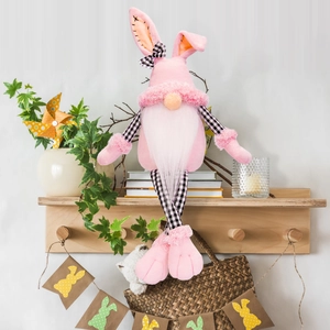 Detail of pink long-legged Easter gnome plush with plaid fabric on a wooden shelf