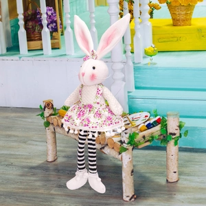 Detail of pink floral Easter bunny plush toy with long striped legs on wooden seat