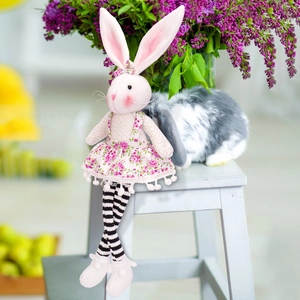 Detail of pink Easter bunny plush toy in floral dress and striped long legs