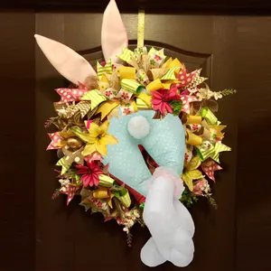 Detailed Easter wreath with polka dot bunny butt and artificial flowers on dark wood door