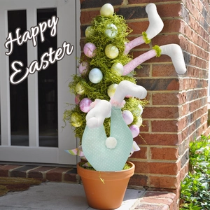 Easter tree decoration featuring stuffed bunny legs and colorful eggs in a clay pot