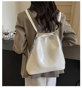 Detail of white patent leather backpack featuring side zipper and glossy finish texture