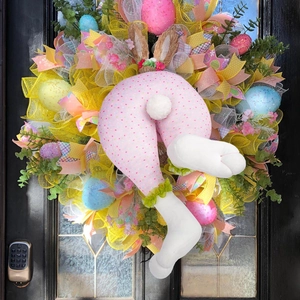 Easter wreath with bunny legs and colorful glitter eggs on a black entrance door
