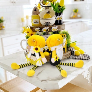 Close-up of plush bumblebee gnomes with striped long legs and sunflower details