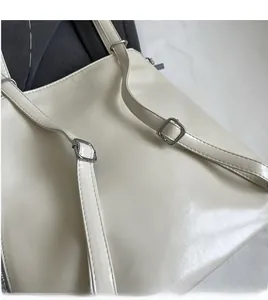 Detail view of adjustable cream tote bag strap with silver buckle and neat stitching