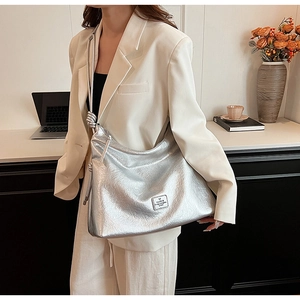 Detail of silver metallic tote bag with crinkled texture and decorative knot strap detail