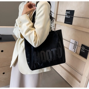 Detail of black tote bag with HOOTO letter patch and silver chain strap on shoulder