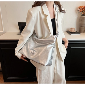 Detail of metallic silver tote bag with unique knotted strap and brand leather tag