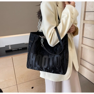 Detail of black wrinkled tote bag with silver chain strap and HOOTO letter design
