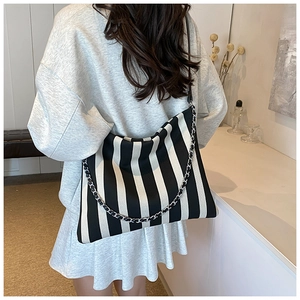 Close-up of black and white vertical striped tote bag with silver woven metal chain detail