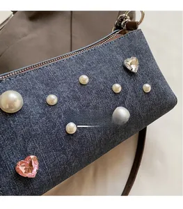 Détail du sac bandoulière en jean avec perles et décorations en cristal de cœur