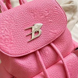 Close-up of pink lychee textured leather backpack with a silver metal B logo hardware buckle