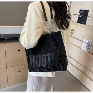 Detail of black HOOTO tote bag with wrinkled texture and silver metal chain strap