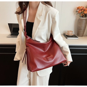 Detail of large dark red leather tote bag with knot strap on a model in office setting
