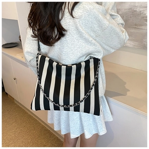 Close-up of black and white vertical striped canvas shoulder bag with silver chain strap