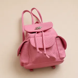 Detail of pink lychee leather backpack showing drawstring closure and metal buckle