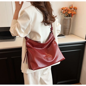 Detail of dark red large tote bag with knotted shoulder strap and glossy texture