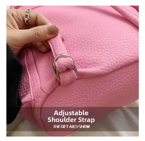 Detail of adjustable silver D-ring and pink pebble grain leather strap on a backpack